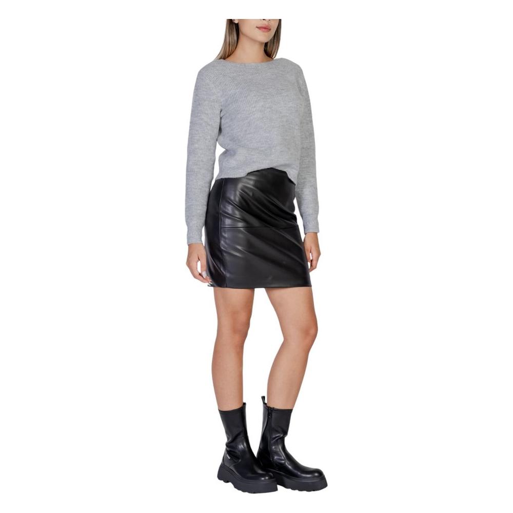 Alt Tag: Woman wearing ICHI black polyethylene skirt from Fall/Winter collection, styled with a grey sweater and black boots.