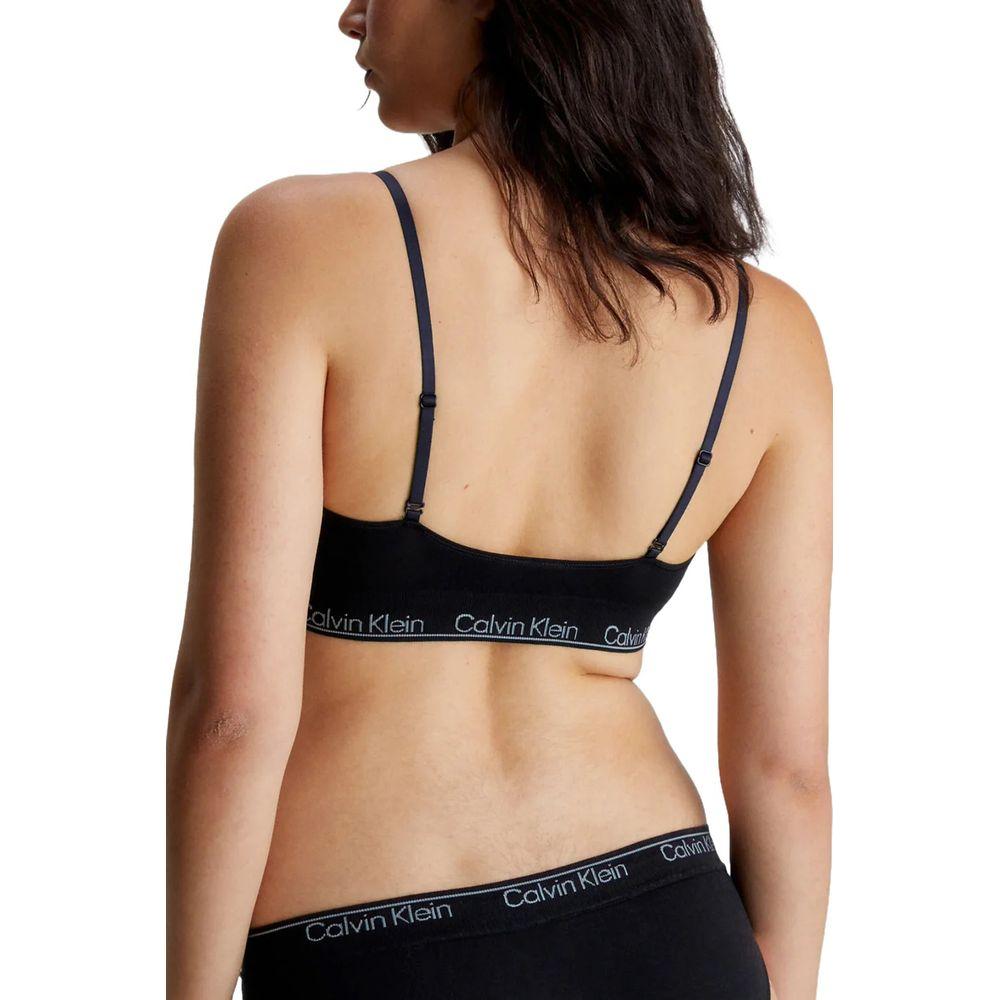 Woman wearing Calvin Klein black lyocell triangle bra and underwear set, back view showcasing minimalist design and comfort.