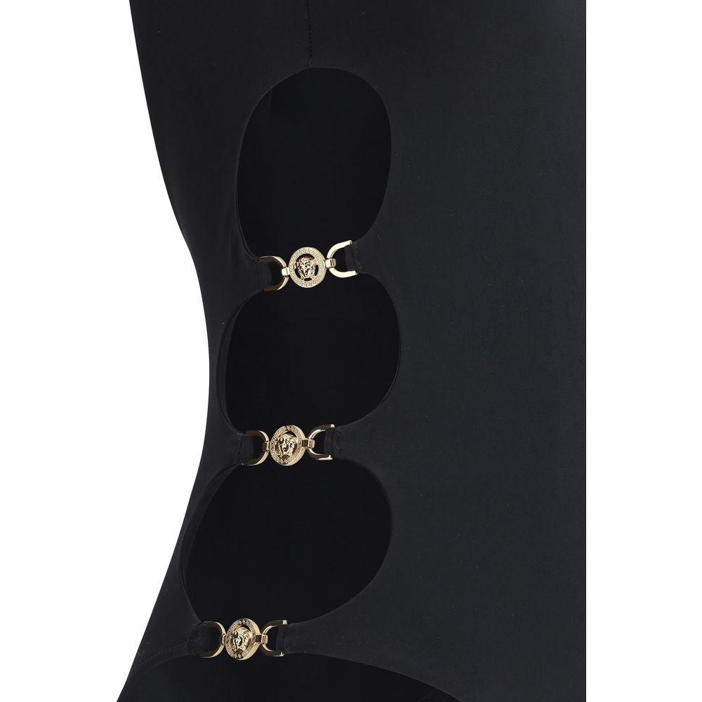 Close-up of Versace one-piece swimsuit with side cut-out details and iconic Medusa logo plaques, featuring a sleek monochrome design.
