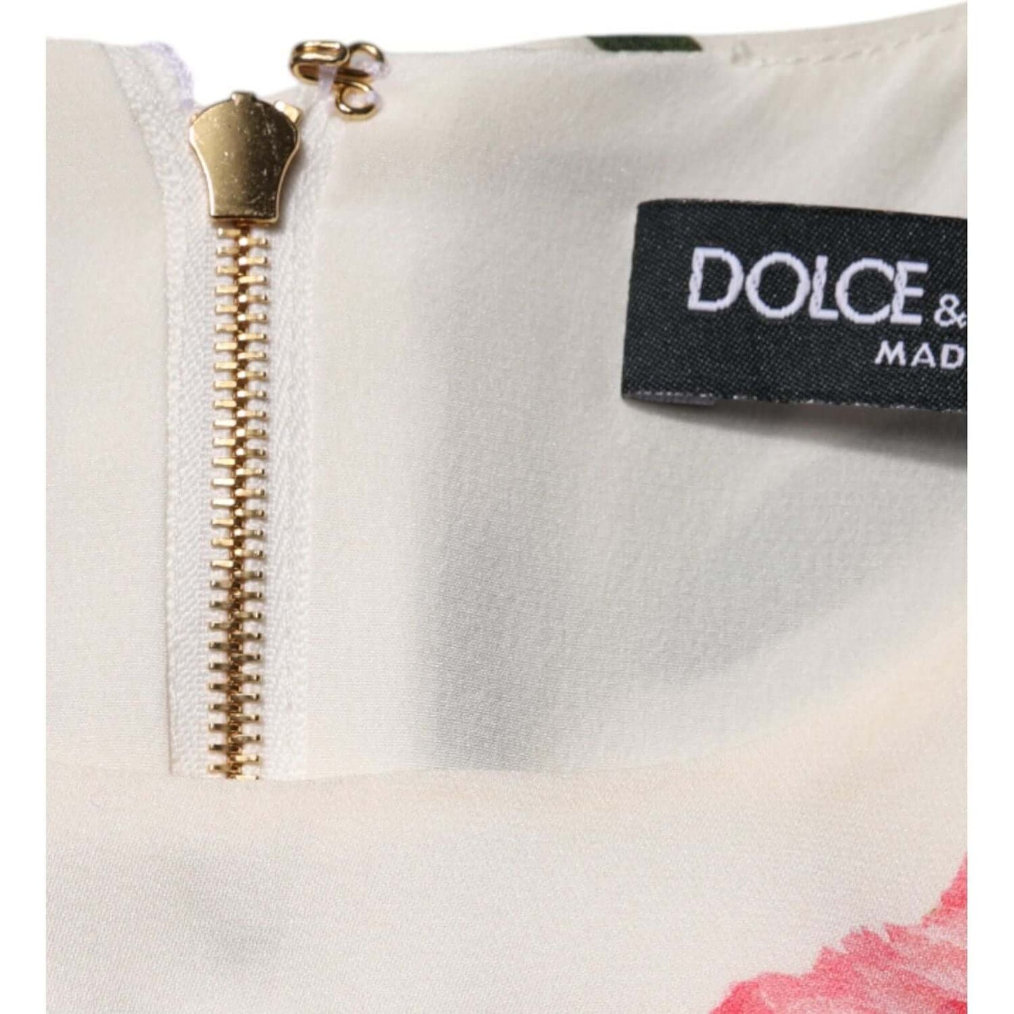 Close-up of Dolce & Gabbana pink floral dress neckline with zipper and logo tag, highlighting makeup stains.