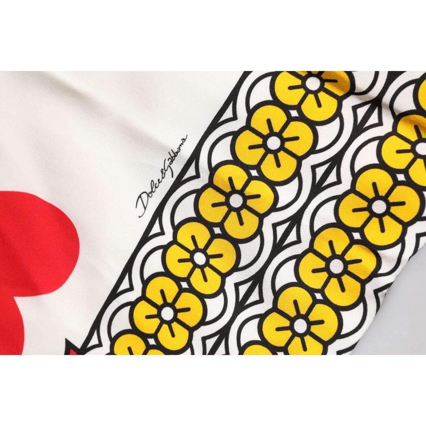 Close-up of Dolce & Gabbana Queen Of Hearts Maxi Dress with floral print and logo detail on white silk fabric.