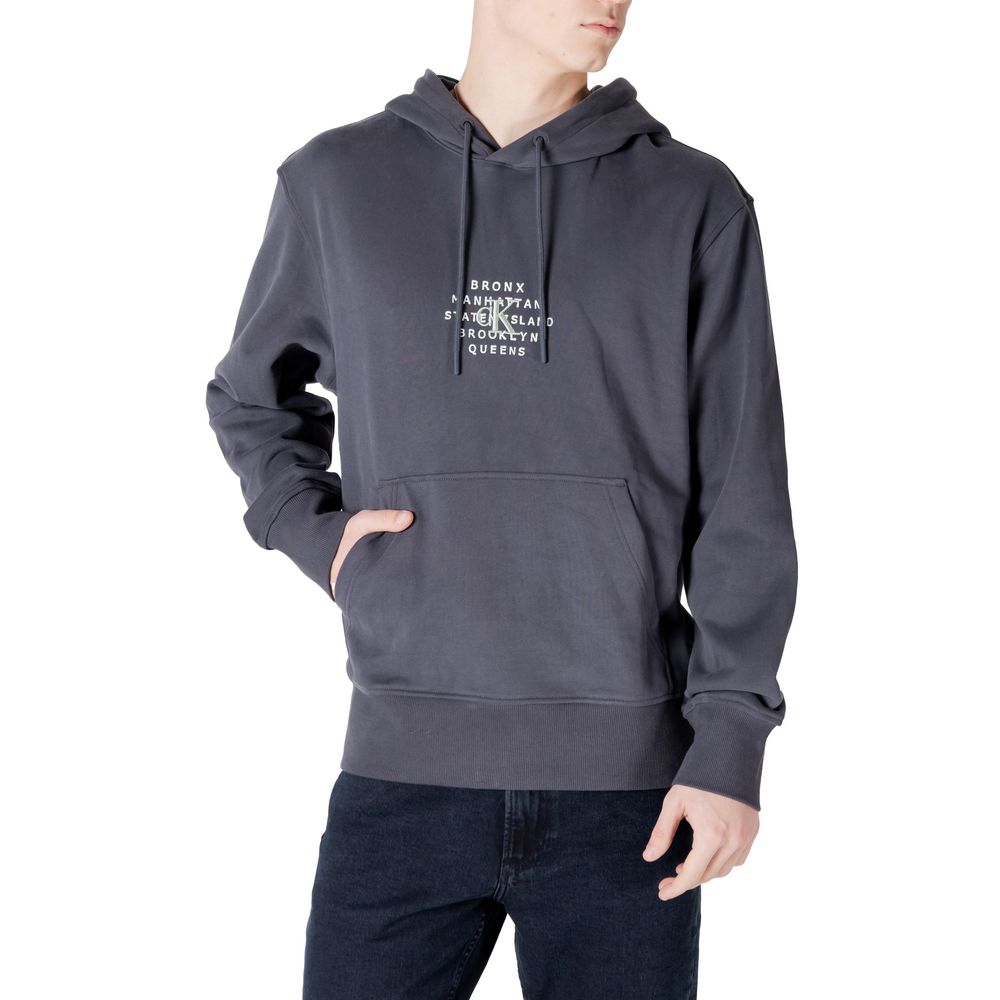 Calvin Klein Jeans Gray Cotton Hoodie featuring NYC stamp graphic, modeled by man wearing black jeans.