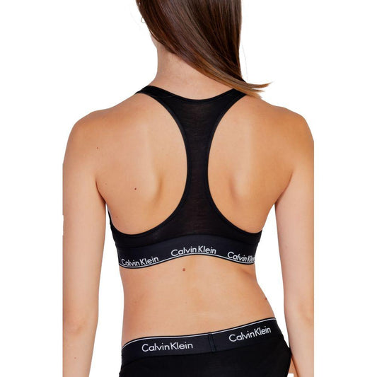 Back view of a woman wearing Calvin Klein black cotton unlined bralette, showing minimalist design and logo waistband.