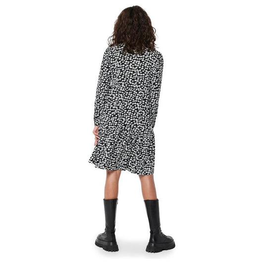 Back view of woman wearing floral black and white midi dress with boots, showcasing fall/winter fashion style.
