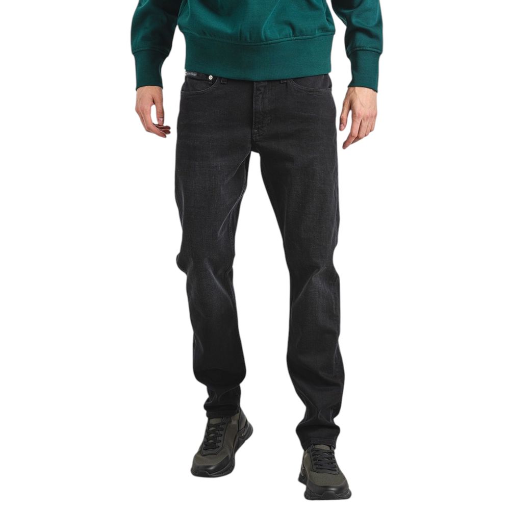 Man wearing Calvin Klein Jeans Black Cotton Slim Fit Jeans showing tapered design.