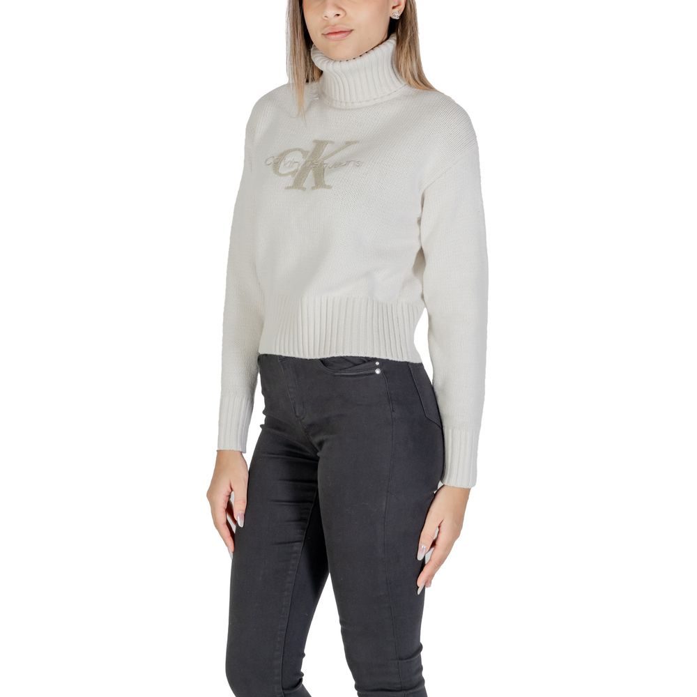Woman wearing Calvin Klein Jeans Cream Cotton Turtleneck with CK logo, showcasing modern cropped fit and ribbed design for cool weather.