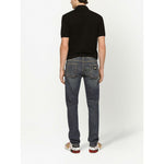Back view of a man wearing a black Dolce & Gabbana Logo cotton polo shirt with jeans and patterned sneakers.