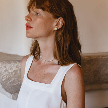 Woman wearing MAJORICA JEWELRY Mod. 17785.00.1.E00.906.1 earrings with white top, showcasing elegant style.