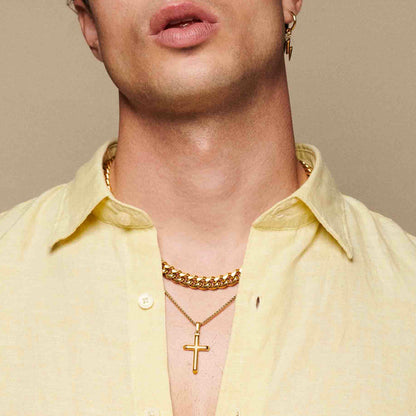 Man wearing a gold chain and cross necklace with a yellow shirt.