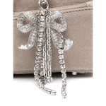 Close-up of silver-tone bow detailing on Self-Portrait suede baguette shoulder bag with grey suede, showcasing luxurious style.
