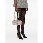 Self-Portrait suede baguette shoulder bag in grey with silver-tone hardware and bow detail, held by model, showcasing top zip and handles.